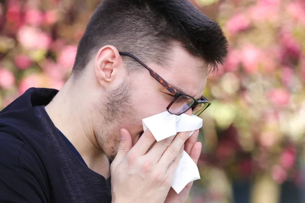 Ill boy with flu is sneezing in the park — Stock Photo, Image