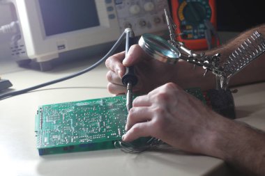 Laboratuvarda lehimdemir ve loupe ile tamir devre kartı