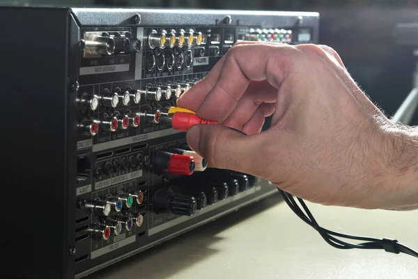 Hombre conectando cables de audio en el panel posterior del amplificador de música — Foto de Stock
