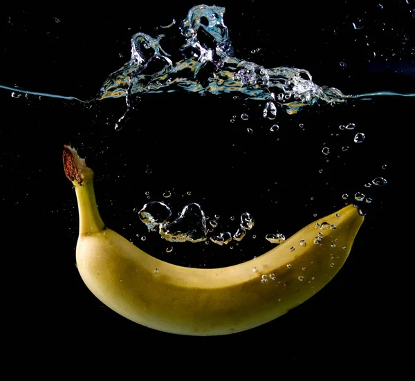 Yellow Banana splashing in water on black