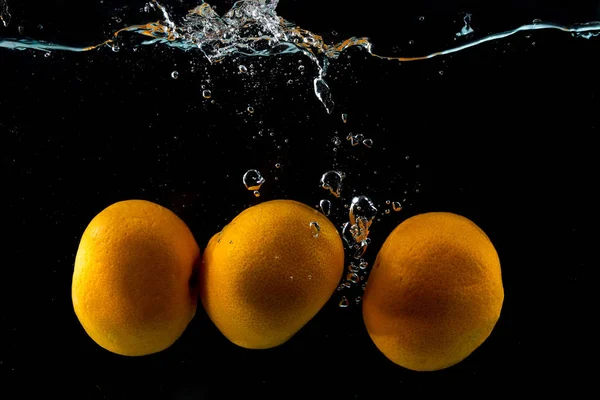 Trzy dojrzałe Clementine w wodzie Splash na czarno — Zdjęcie stockowe