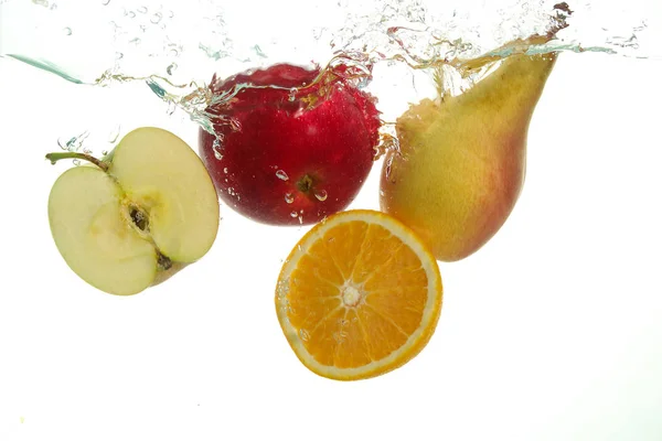 Frutos varius pêra de maçã e salpicos de laranja na água em branco — Fotografia de Stock