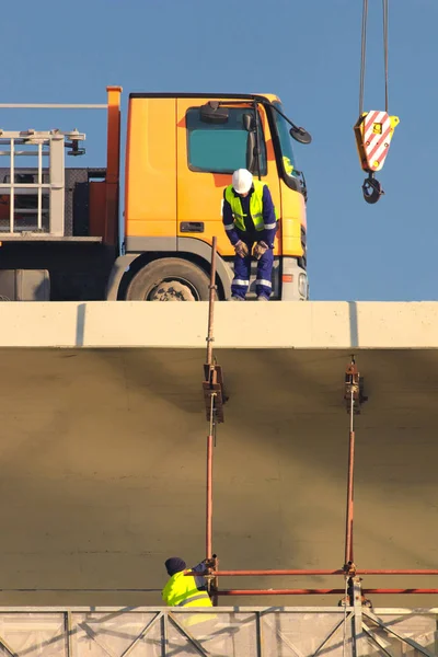 Dos trabajadores, grúa y pista en el área de reconstrucción — Foto de Stock