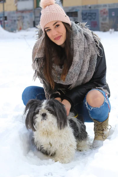 Młoda kobieta ze swoim psem shih-tzu w śniegu — Zdjęcie stockowe