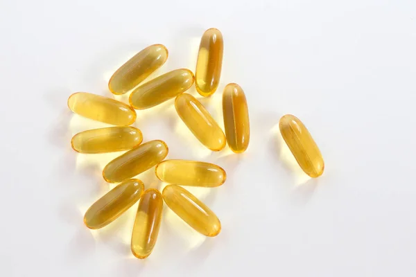 Vista superior de cápsulas de aceite de pescado amarillo, omega 3, en blanco —  Fotos de Stock