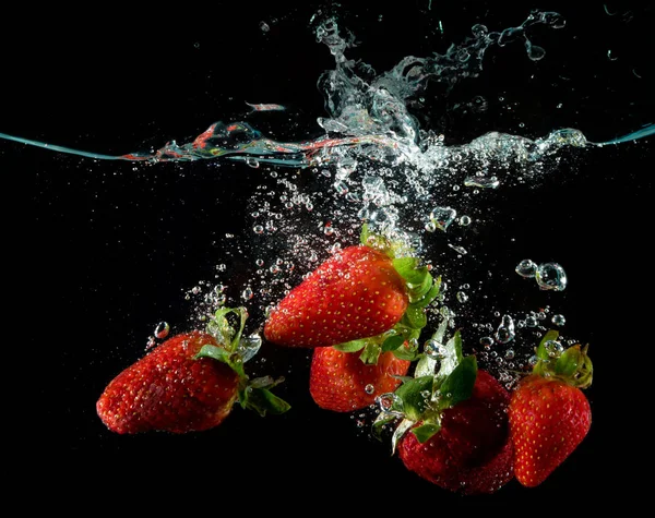 Siyah üzerinde suya sıçraması taze çilek
