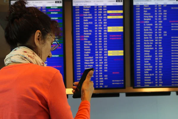 Літня жінка з мобільним телефоном шукає розклад польотів — стокове фото
