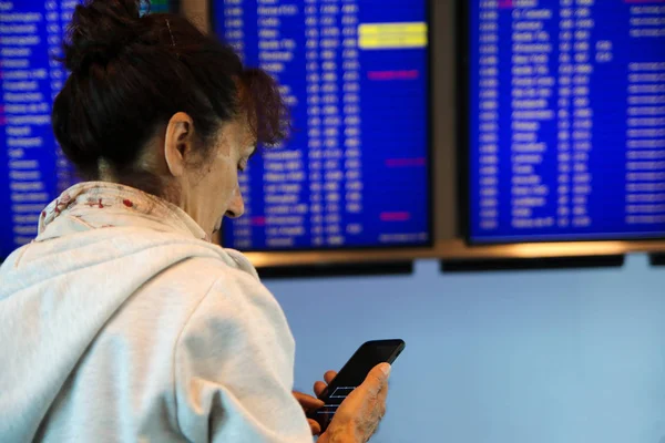 Жінка з мобільним телефоном шукає розклад польотів на timeta — стокове фото
