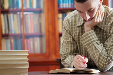 Genç çocuk kütüphanede öğreniyor.