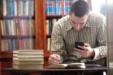 Genç çocuk öğrenci bir kütüphanede bir sınav hazırlar