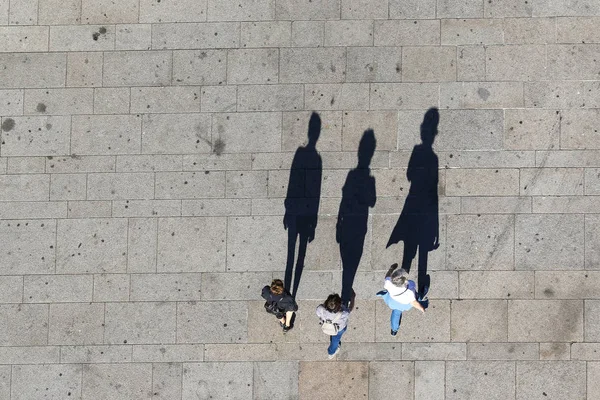 Draufsicht auf drei Touristen mit Schatten auf der Straße Stockfoto