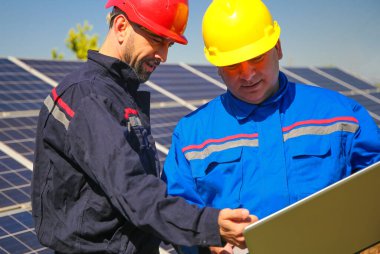 Yeşil enerji, elektrik santrali ve dizüstü bilgisayarı olan iki tehnician.