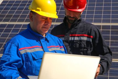 Yeşil enerji, dizüstü bilgisayarı ve güneş panelleri olan iki teknisyen.
