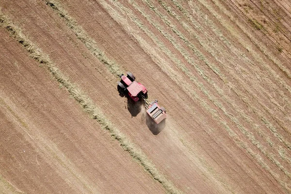 红色拖拉机在田里把干草捆起来 — 图库照片