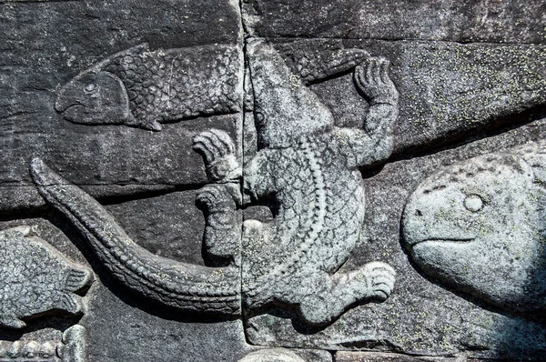 Ancient Khmer bas relief carving showing a crocodile catching a fish in the Tonle Sap lake. Bayon Temple, Angkor Thom, Siem Reap, Cambodia.