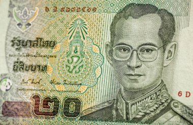 Tayland 'dan kullanılmış bir 20 Baht banknotu. Hafif bir açıyla fotoğraflandı ve Silahlı Kuvvetler Yüksek Komutanı üniforması içindeki hükümdar Kral Bhumibol Adulyadej 'e odaklandı..