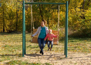 Anne ile çocuk binmek sonbaharda bir salıncak üzerinde