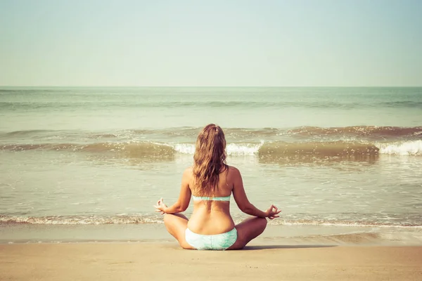 Young woman meditates sitting on the ocean — Stock Photo, Image