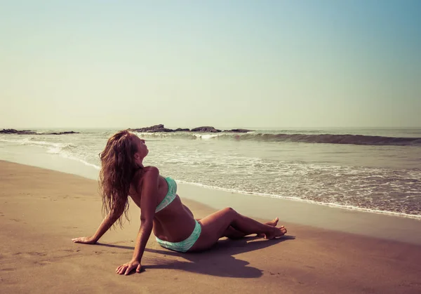 젊은 여자는 바다의 배경에 대해 해변에 누워있다 — 스톡 사진