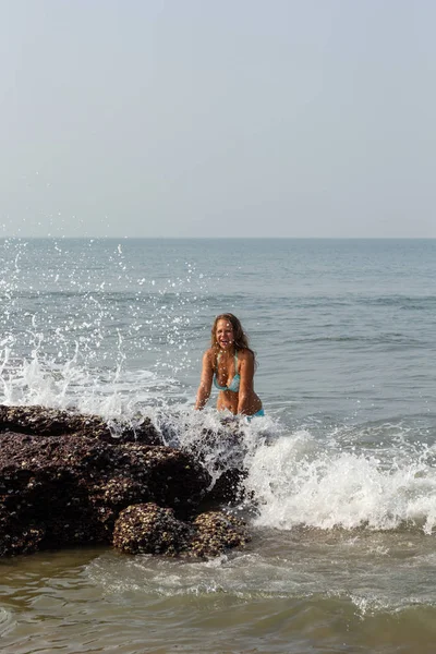 Ritratto di una giovane donna sullo sfondo di onde e pietre — Foto Stock
