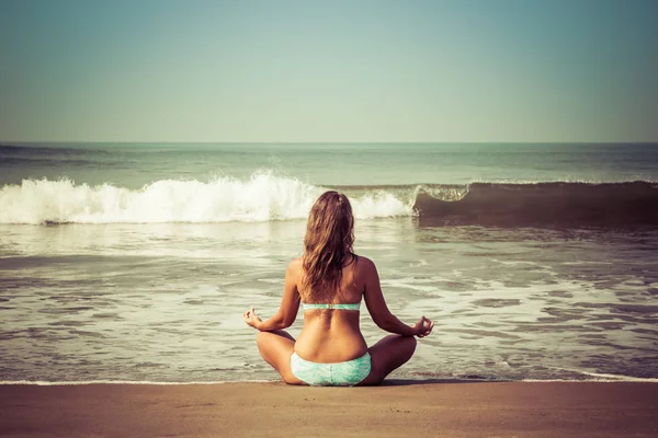 Young woman meditates sitting on the ocean — Stock Photo, Image