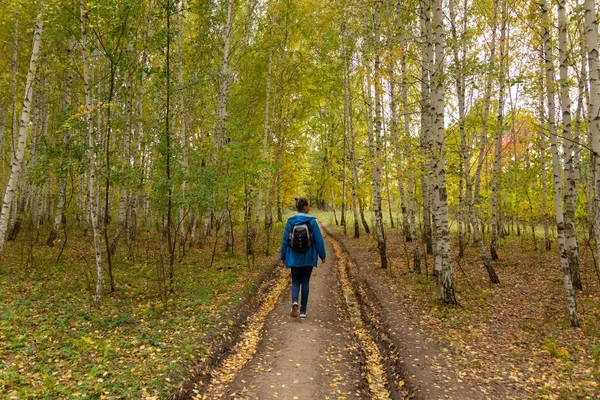 Mädchen mit Rucksack spaziert durch den Herbstwald — Stockfoto