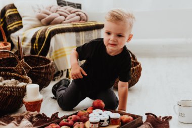 İki yaşındaki havalı hippi çocuk, sonbahar dekorunun süslü fotoğraf sahasında güzel, parlak sonbahar yapraklarıyla poz veriyor. Sıcak atmosfer
