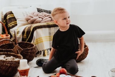 İki yaşındaki havalı hippi çocuk, sonbahar dekorunun süslü fotoğraf sahasında güzel, parlak sonbahar yapraklarıyla poz veriyor. Sıcak atmosfer