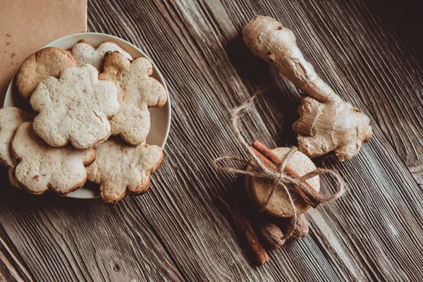 Close up of homemade ginger cookies, cinnamon, ginger on a wooden table. Copy space. Vintage toned image, flat lay