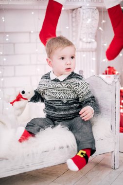 Genç bir çocuğun Noel portresi şöminenin ve Noel ağacının etrafında rahat bir atmosfer.