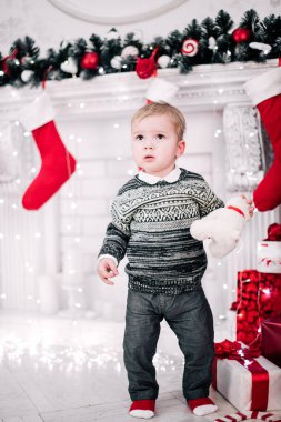 Genç bir çocuğun Noel portresi şöminenin ve Noel ağacının etrafında rahat bir atmosfer.