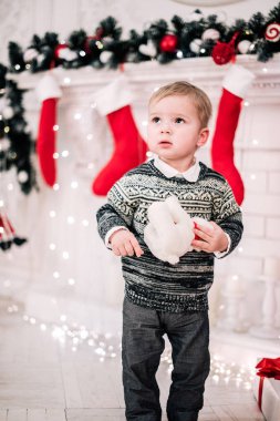 Genç bir çocuğun Noel portresi şöminenin ve Noel ağacının etrafında rahat bir atmosfer.