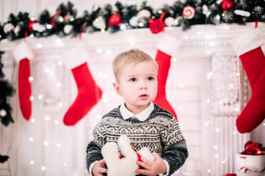 Genç bir çocuğun Noel portresi şöminenin ve Noel ağacının etrafında rahat bir atmosfer.