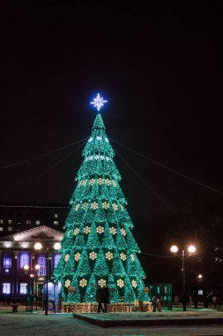 Parlak çelenk ve kış sokakta yıldız Parlatıcı ışıkları ile büyük bir Noel ağacı. Gomel, Beyaz Rusya'nın şehrin dekorasyon tatil için.