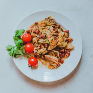 Beyaz tabakta kiraz domatesli fasulye güveç 