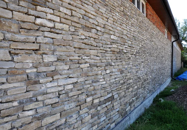 The wall of the house is constructed of a natural river stone