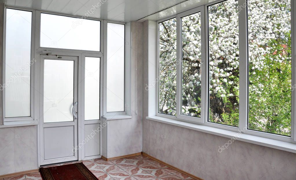 Metal-plastic doors and windows in the loggia. View interior from the middle, outside blossom apple