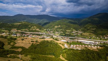 Küçük kırsal köyü çevreleyen yemyeşil tepeler dramatik gökyüzü altında