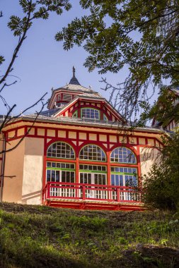 Geniş kemerli pencereleri ve süslü kırmızı süslemeleri olan renkli tarihi bina