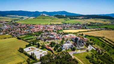 Hava manzarası yeşil arazi tepeleriyle çevrili küçük kırsal kasabayı gösteriyor.