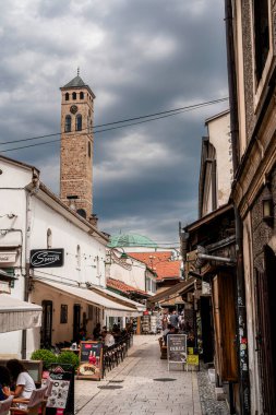 Dar kaldırım taşı caddesi dramatik bulutlu gökyüzünün altındaki kafelerle dolu.