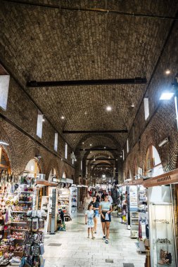 İnsanlar kemerli tuğla tavanlı tarihi iç pazarda geziniyorlar.