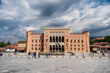 Dramatik bulutlu gökyüzünün altında kemerlerin yer aldığı tarihi bina
