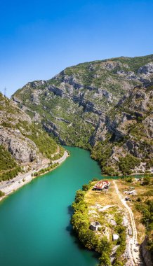 Turkuaz nehri açık mavi gökyüzünün altında kayalık dağ kanyonunda kıvrılıyor.