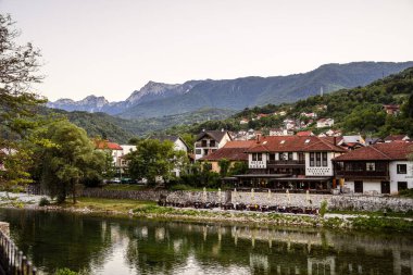 Nehre yansıyan yeşil tepelerin arasına kurulmuş resim gibi bir köy.