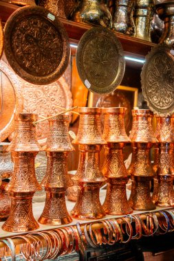 Doldurulmuş bakır bardaklar süslü metal tepsiler arasında ışığı yansıtıyor