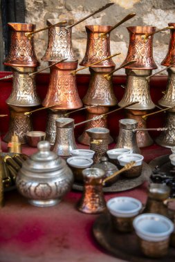 Kırmızı yüzeye dizilmiş klasik bakır kahve demlikleri ve fincanları