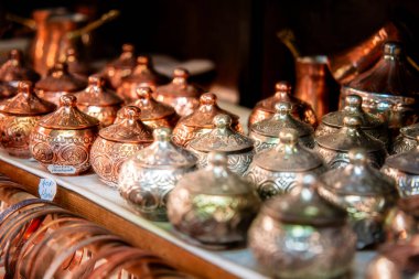 Parlak metal kaplar pazarda karmaşık desenler sergiliyor.