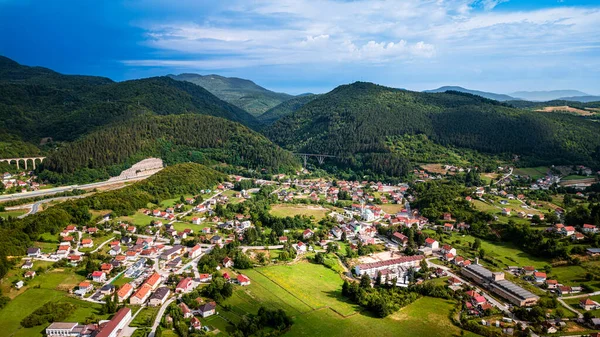 Gökyüzü manzarası yeşil ormanlık tepelerin arasında küçük bir köy olduğunu gösteriyor.