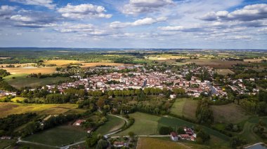 Expansive rural landscape surrounding small village under blue sky